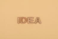 Wooden letters forming 'IDEA' on a plain beige surface, representing creativity.